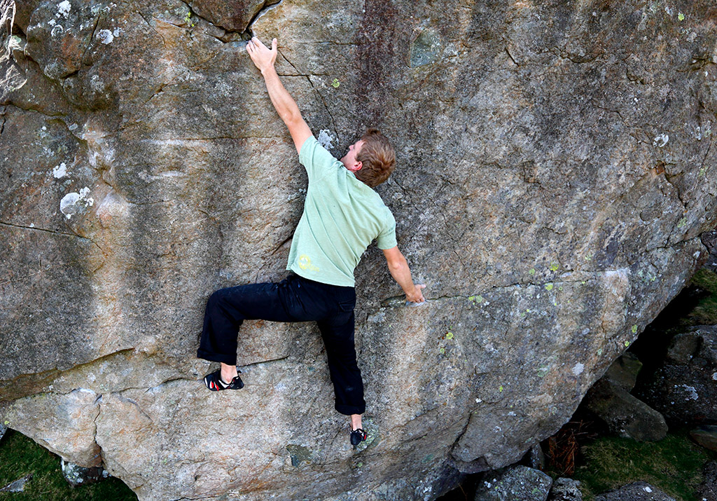 Adam Hocking makes the stretch from the undercut on the brilliant Rouse's Wall (V5) on Boardman's Boulder. Photo: © David Simmonite